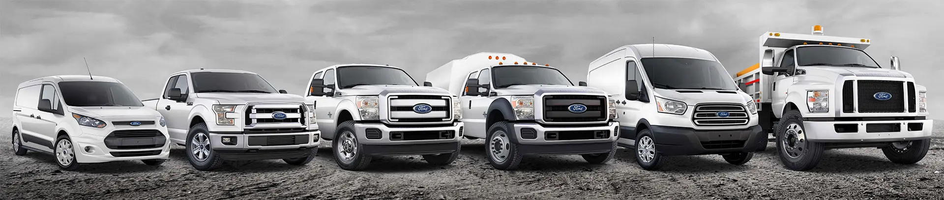 Two white trucks parked in a dirt field.