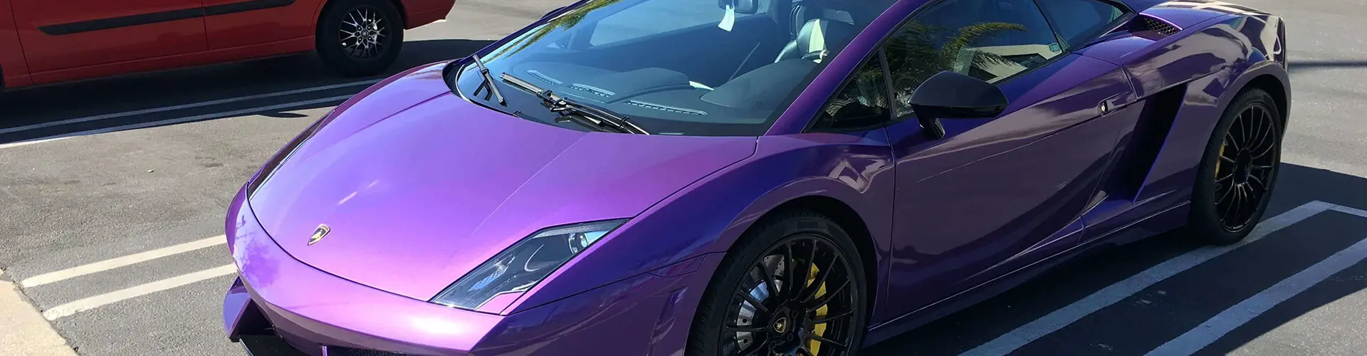 A purple car with yellow wheels parked in front of it.