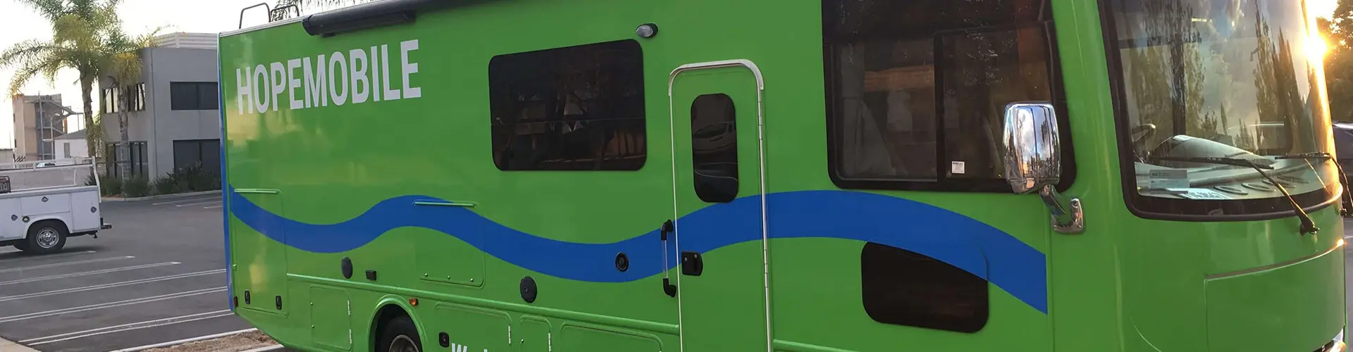 A green bus with blue stripes on the side.