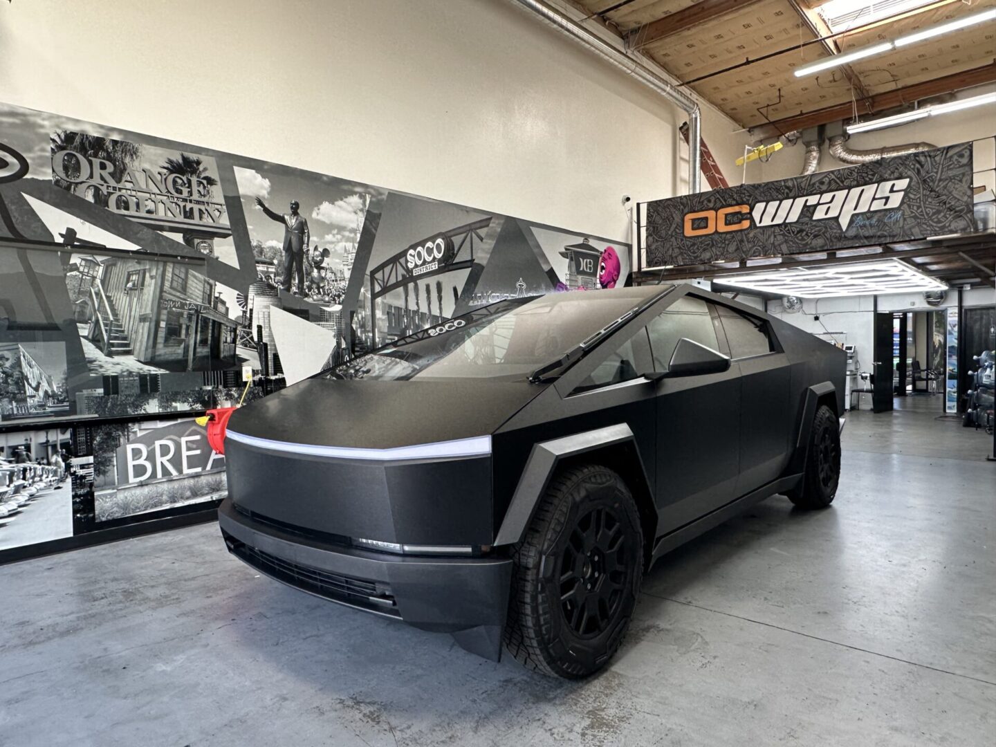 A black car is parked in front of a wall.